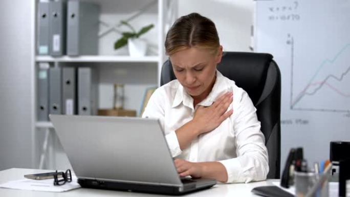 在笔记本电脑上工作的女人感到心脏疼痛，神经紧张，心脏病学