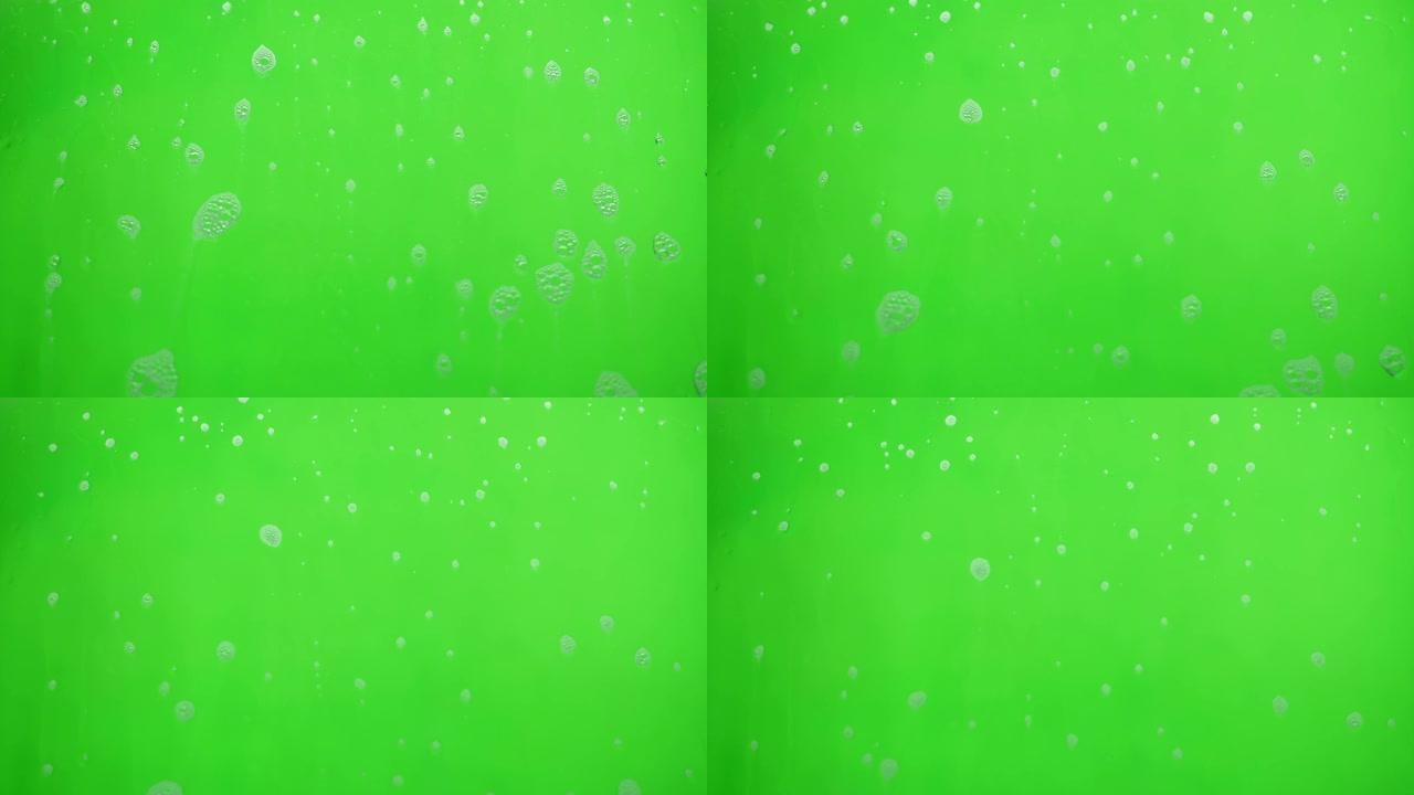 肥皂在绿色背景上流动的泡沫。