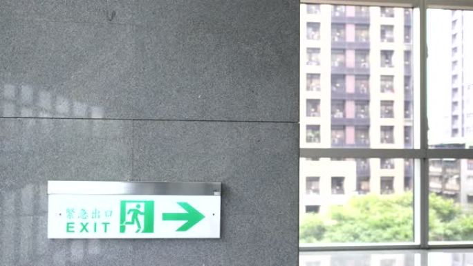 紧急出口，逃生路线标志。公共场所现代建筑中的位置。四个汉字表示紧急出口。模糊的背景是透明的窗户。