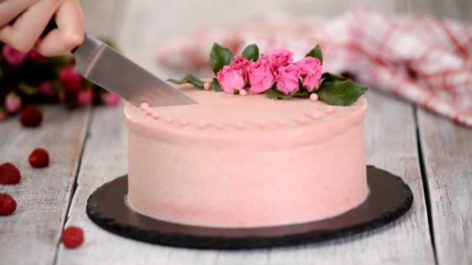 女人用玫瑰切一个漂亮的蛋糕。甜食