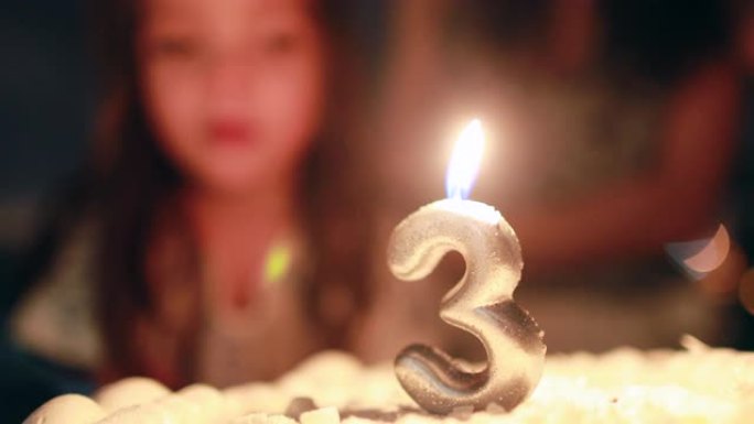 儿童在庆祝三岁的生日蛋糕上吹蜡烛