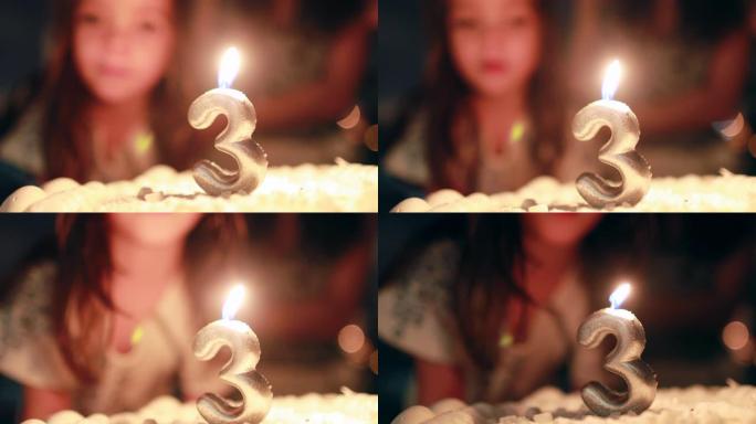 儿童在庆祝三岁的生日蛋糕上吹蜡烛