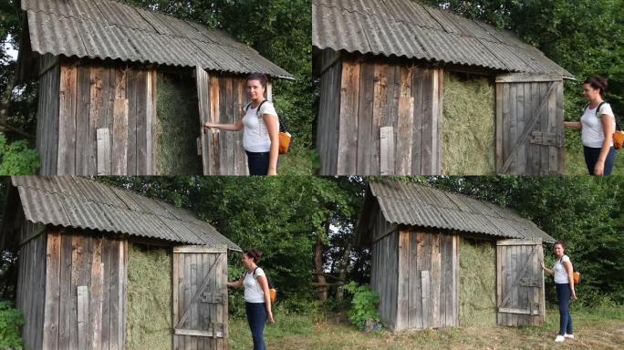 一个背着背包的女孩打开了一个装满干草的谷仓。