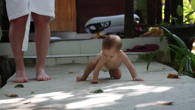 婴儿婴儿坐在街上的地上。从地板上捡起来吃东西。