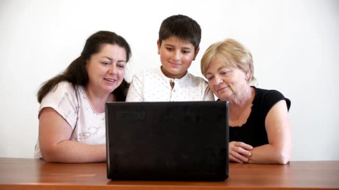一个孩子，他的母亲和祖母在笔记本电脑中通过视频通信进行交流