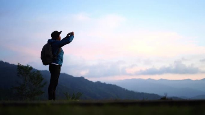 越野跑运动员在跑步时在山里用手机拍照。