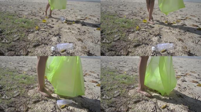 年轻女孩在沙滩上收集垃圾成绿色塑料袋，塑料瓶被收集在沙滩上，志愿者清理海滩。