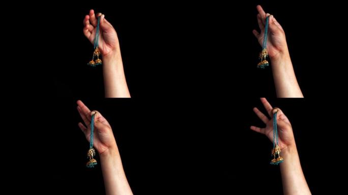 一只女性的手出现，并显示出黑色的蓝色钻石耳环。