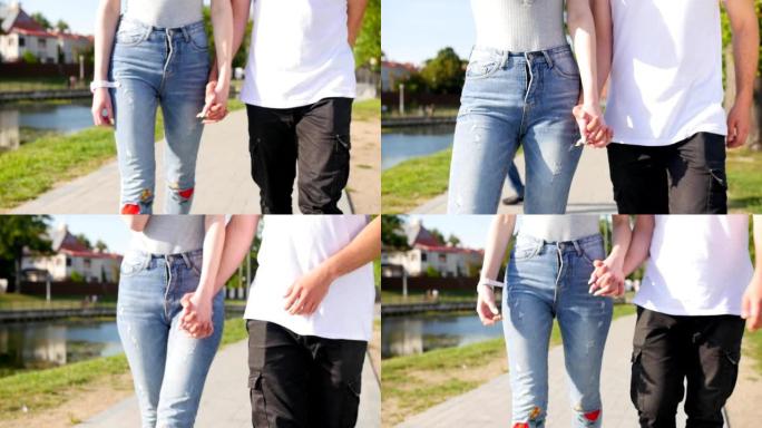 两个恋人携手的特写镜头。男人和女人牵手在公园散步的细节轮廓。夫妻信任、爱和幸福的概念。