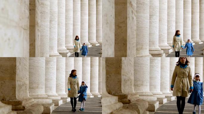 女人和女儿在梵蒂冈圣彼得罗广场的柱子之间行走