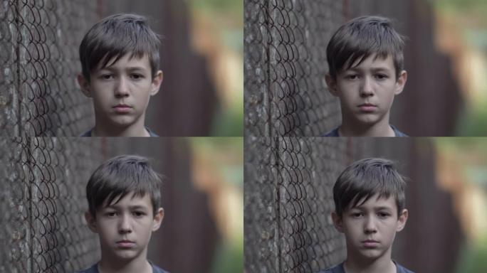 难民悲伤的男孩同情地看着相机，脸上的疼痛，移动的相机