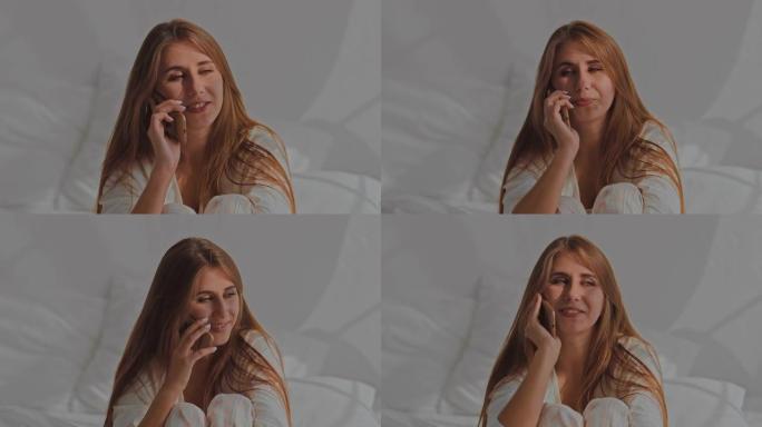 漂亮的女孩在电话里聊天，穿着睡衣坐在床上。早上醒来，和女朋友聊天。肖像视图。