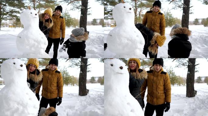 幸福的家庭妈妈，爸爸和儿子在冬季城市公园堆雪人。