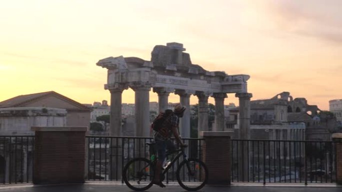 日出时在罗马论坛上背着背包和骑自行车的年轻人游客。从全景的角度来看，意大利罗马的历史帝国罗马罗马。