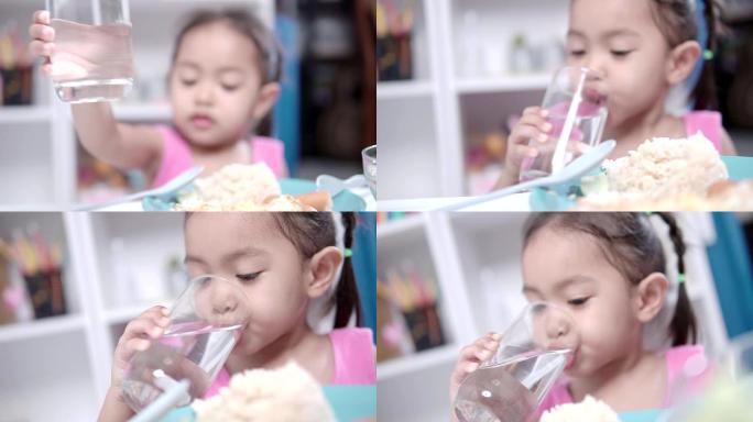 一个小女孩吃完后喝水。