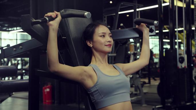 女性穿运动内衣在健身房使用器材锻炼