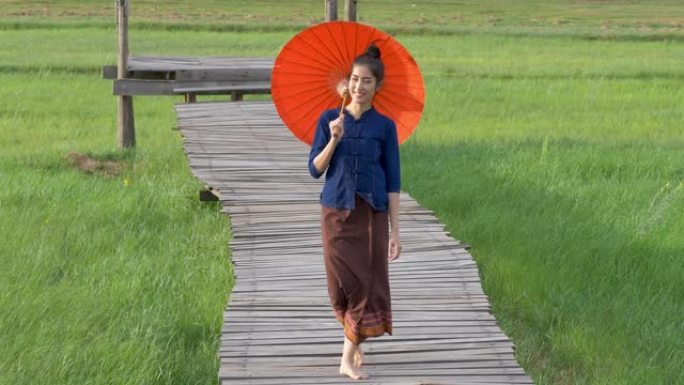 泰国妇女穿着传统风格的红色雨伞。