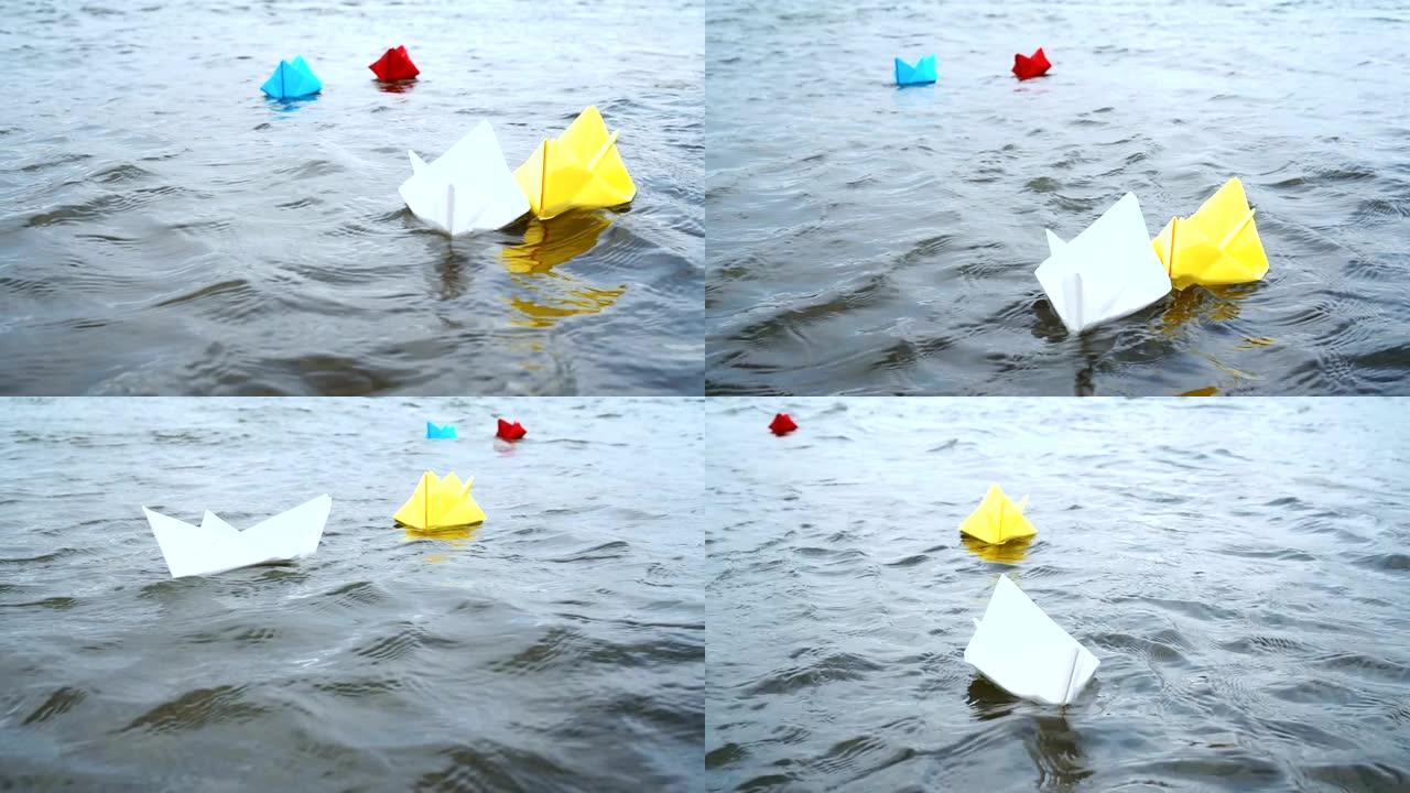 四艘五彩纸船在浪漫的日落时在水上航行。折纸