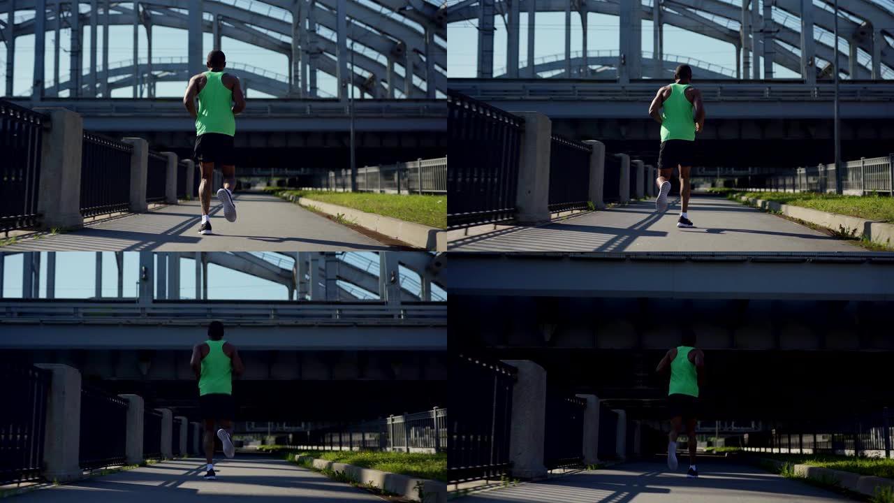 田径非洲人在绿色背心和运动短裤在桥上慢跑马拉松练习，低角度后视镜全程跟随射击