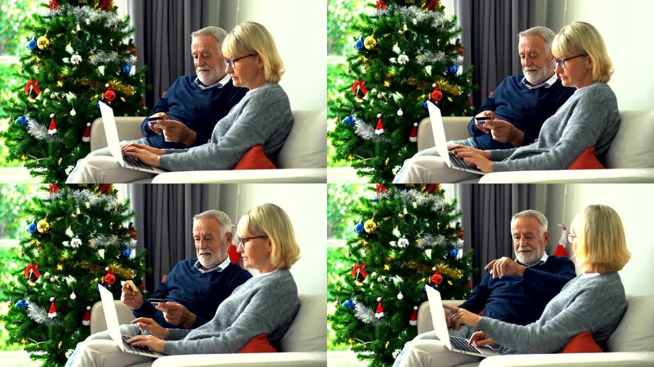4k微笑的高级夫妇持有Visa信用卡，在圣诞节用笔记本电脑在线购物时