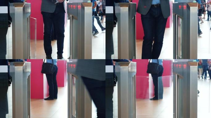 穿着灰色西装夹克和蓝色牛仔裤的男人通过带条形码扫描仪的电子旋转闸门。媒体。商务中心的访问控制，特写