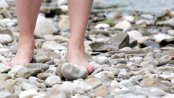 成年妇女赤脚在河岸的鹅卵石上行走