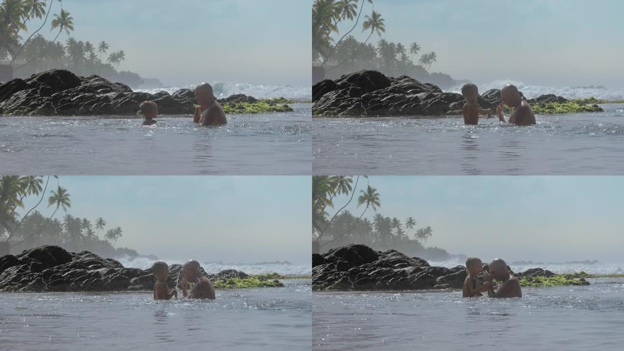 小孩和爸爸在岩石上泼水玩耍