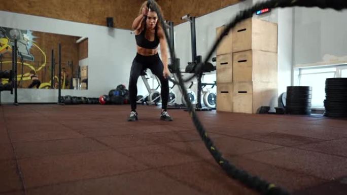 运动的年轻女子在健身房用绳子做健身房锻炼。