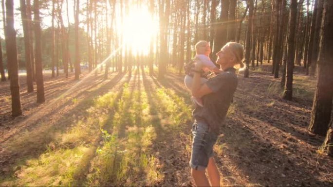 父亲在日落时与小女儿在森林里玩耍