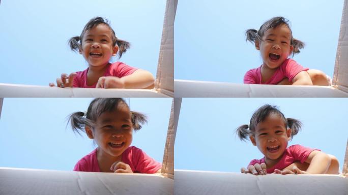 可爱的亚洲儿童女孩在春天玩得开心，微笑着看着明亮的天空背景的相机。