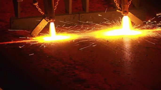 气体切割钢板，金属厂，室内。火花飞舞钢管的生产。植物上有闪光的气体切割金属板。