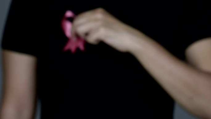 女人向相机展示粉红色的乳腺癌意识丝带