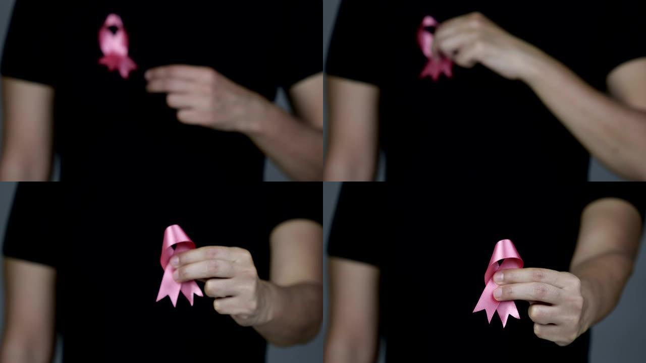 女人向相机展示粉红色的乳腺癌意识丝带