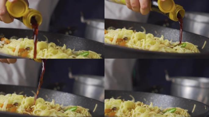 女士将鱼露倒在炒菜上，用米粉放在平底锅上。中国菜。素食节。