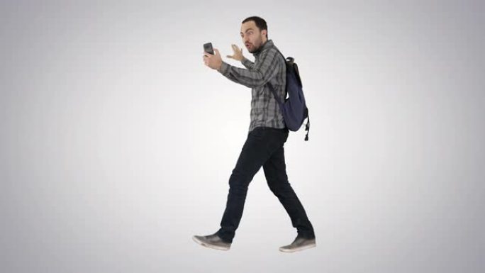 年轻快乐的微笑男子背包记录vlog博客与他的手机在渐变背景