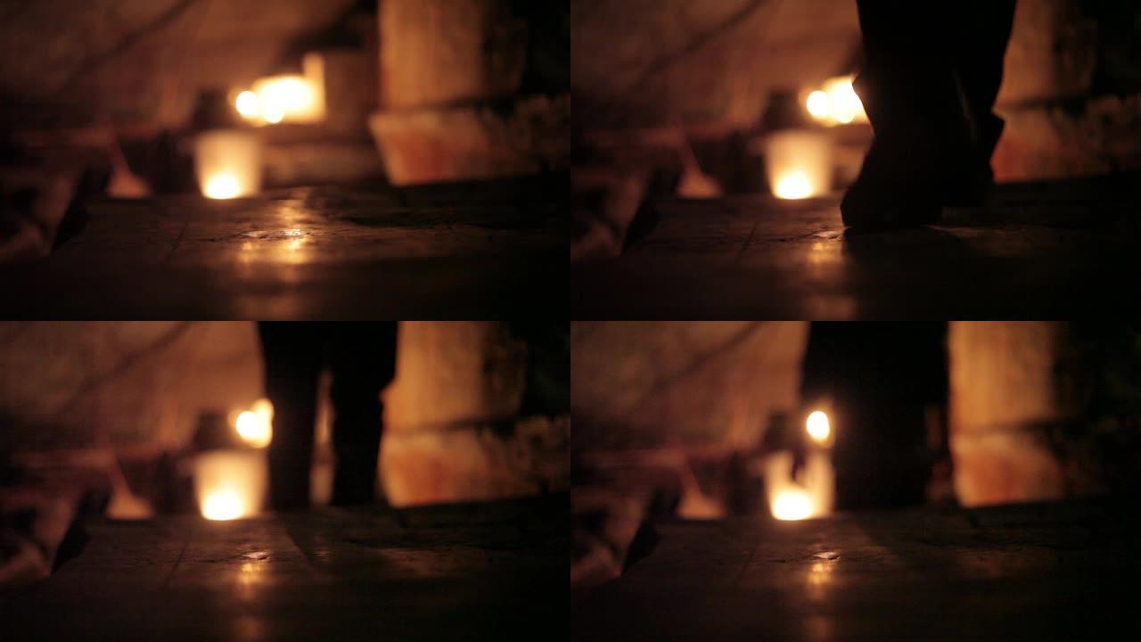 在令人毛骨悚然的黑暗位置使用蜡烛照亮了走下楼梯的人形/身体的轮廓。