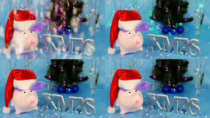 蓝色背景上的圣诞树背景上的红色圣诞老人帽子上的毛绒玩具粉红猪，一杯香槟，一个挡板爆炸，新年的金属丝瀑