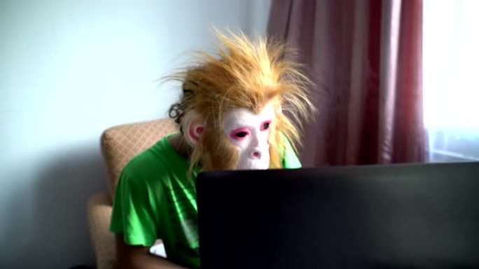 猴子面具里的滑稽男人在电脑后面工作。幽默超现实。拖延概念