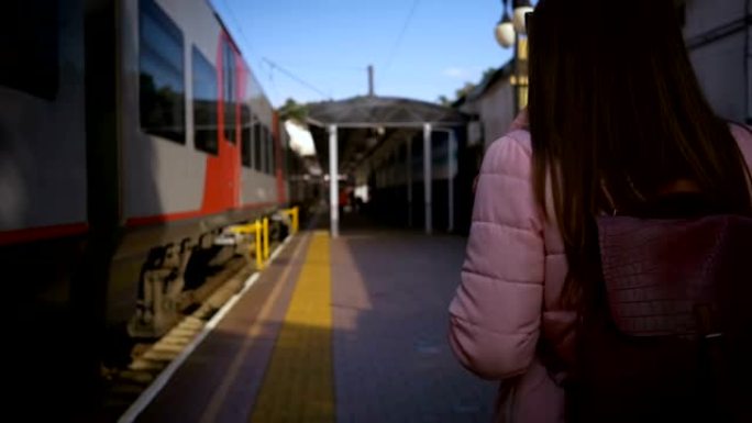 年轻漂亮的女人沿着火车沿着火车站行走