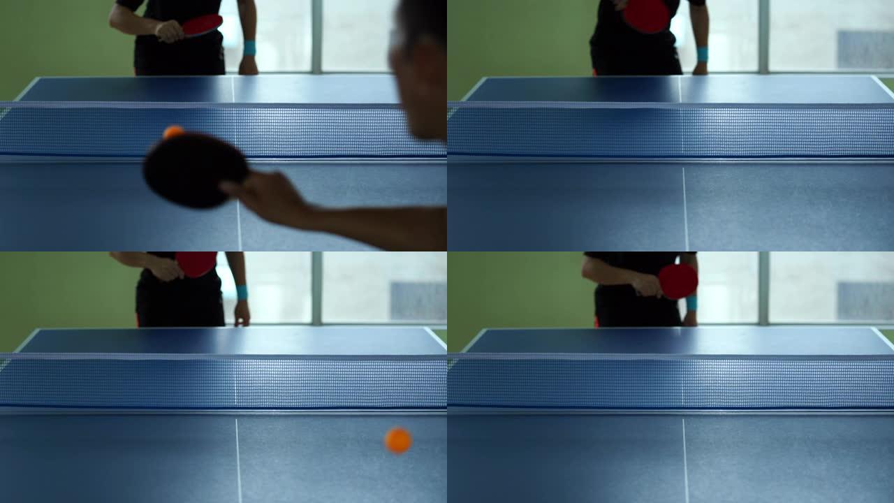 男性在体育馆内用球拍和球打乒乓球