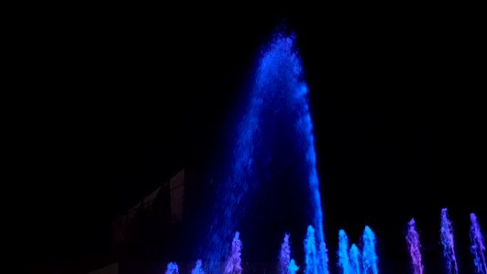 喷泉的水柱在夜空中被蓝光照亮