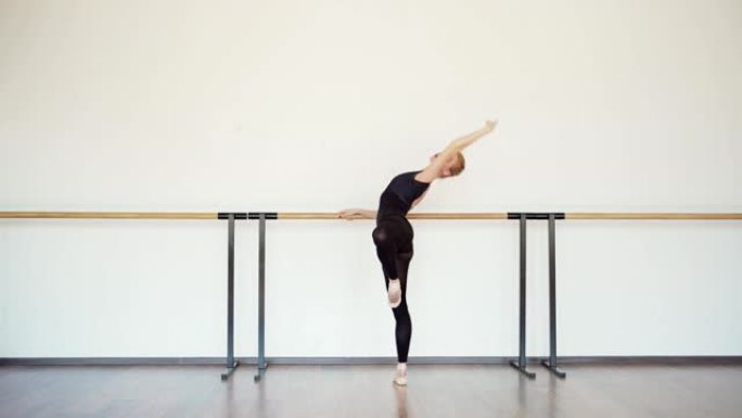 在芭蕾舞工作室的巴雷练习的黑色紧身衣中优雅的readhead年轻芭蕾舞演员的侧视图跟踪镜头