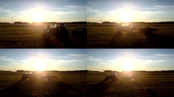 拖拉机方形打包机剪影在明亮的夕阳下移动