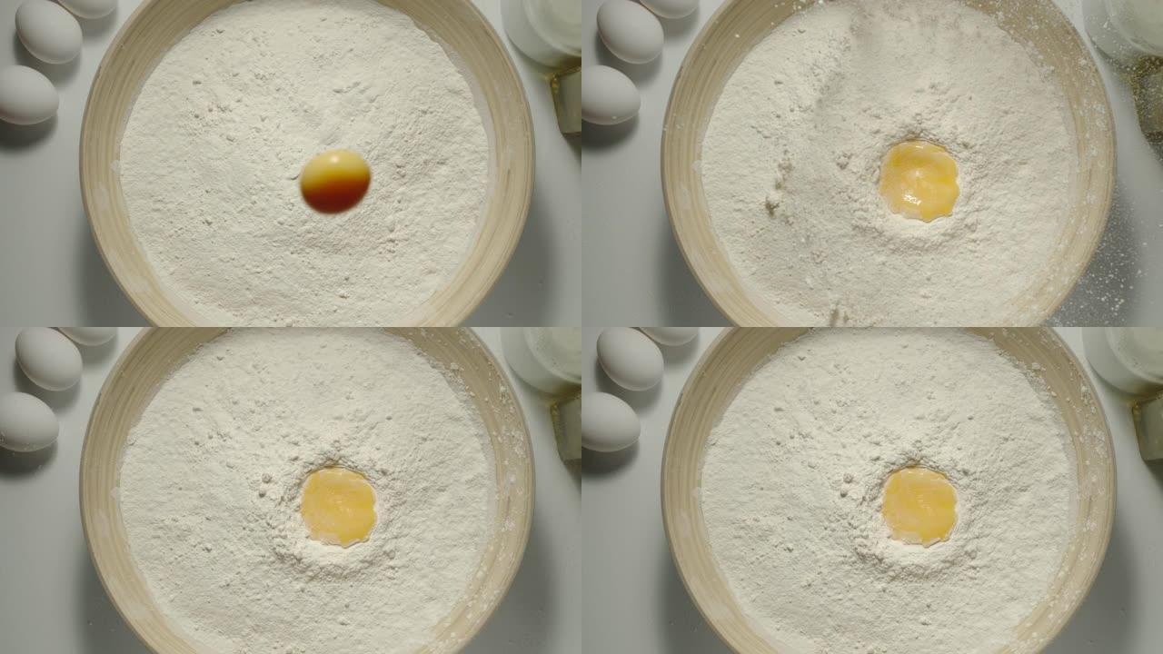 俯视图: 鸡蛋掉入桌子上的一碗面粉中