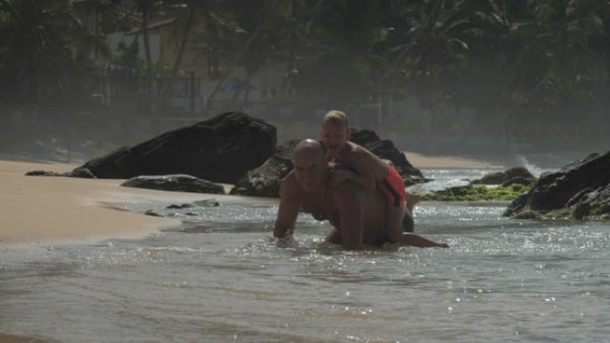 爸爸在海滩上背着小男孩在海里玩得很开心
