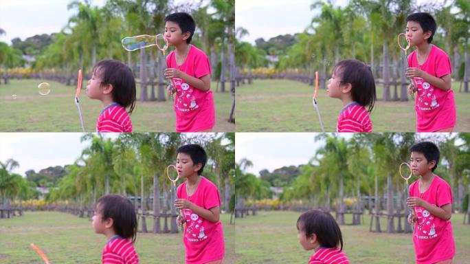 亚洲快乐小孩在花园里吹泡泡魔杖肥皂的慢动作镜头