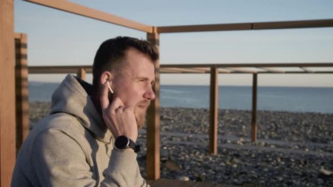 男人正坐在海边检查他的耳朵里的免提
