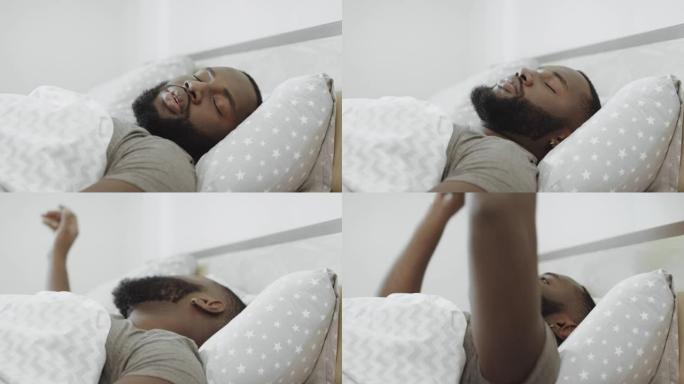 黑人早上睡在床上。年轻人用枕头遮头。