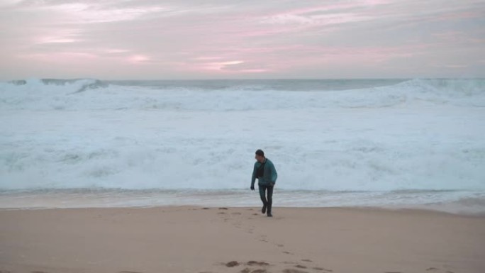 在多云寒冷的天气里，男孩独自走在空旷的海岸上。男孩骑车去迎接大海。他从海浪中逃脱。