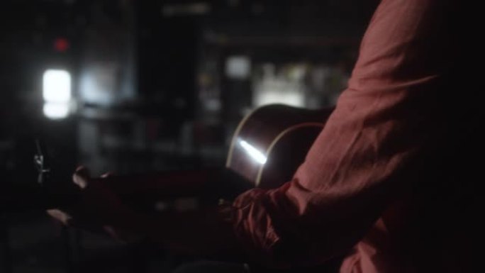 一位拉丁裔音乐家在一个昏暗的空酒吧里演奏木吉他